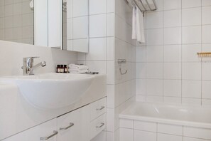 Een moderne badkamer met een wit wastafelmeubel, spiegel en bad.