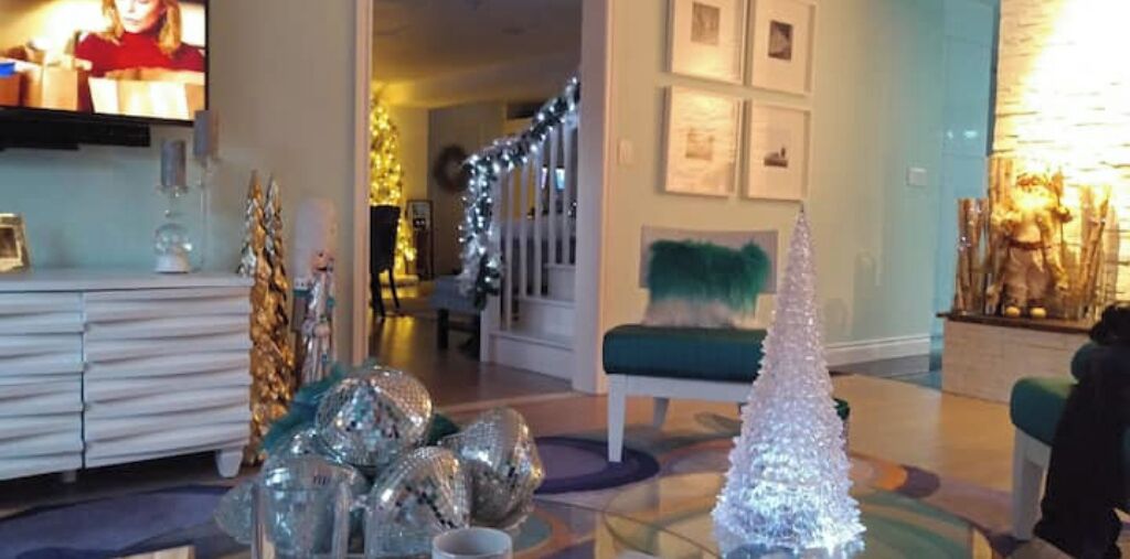Un salon avec une table basse en verre, un canapé blanc et un sapin de Noël.