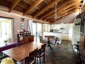 Una cucina rustica con travi in legno, un'area pranzo con tavolo e sedie, e un muro in mattoni.
