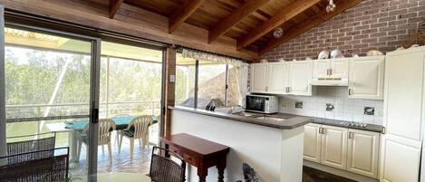 Una cocina con armarios blancos, un microondas y un comedor con mesa y sillas.