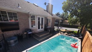 Un jardin avec un jacuzzi, une terrasse en bois et une maison en briques.