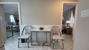 A dining area with a table and two chairs, a window with a view, and a patterned floor.