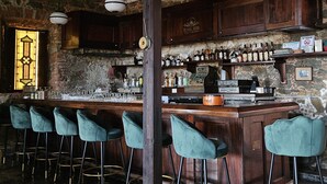 A bar area with wooden bar stools, a stone wall, and a variety of bottles on shelves. - Hotel 1829 (St. Thomas)