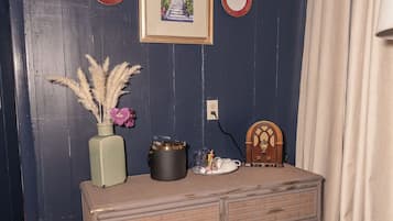 Una habitació amb un taulell, un ram de plantes seques, un quadre amb marc i una paret amb ornaments circulars.
