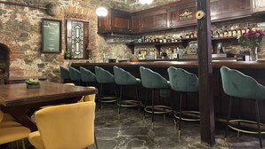 A bar area with a stone wall, wooden bar counter, and bar stools. - Hotel 1829 (St. Thomas)