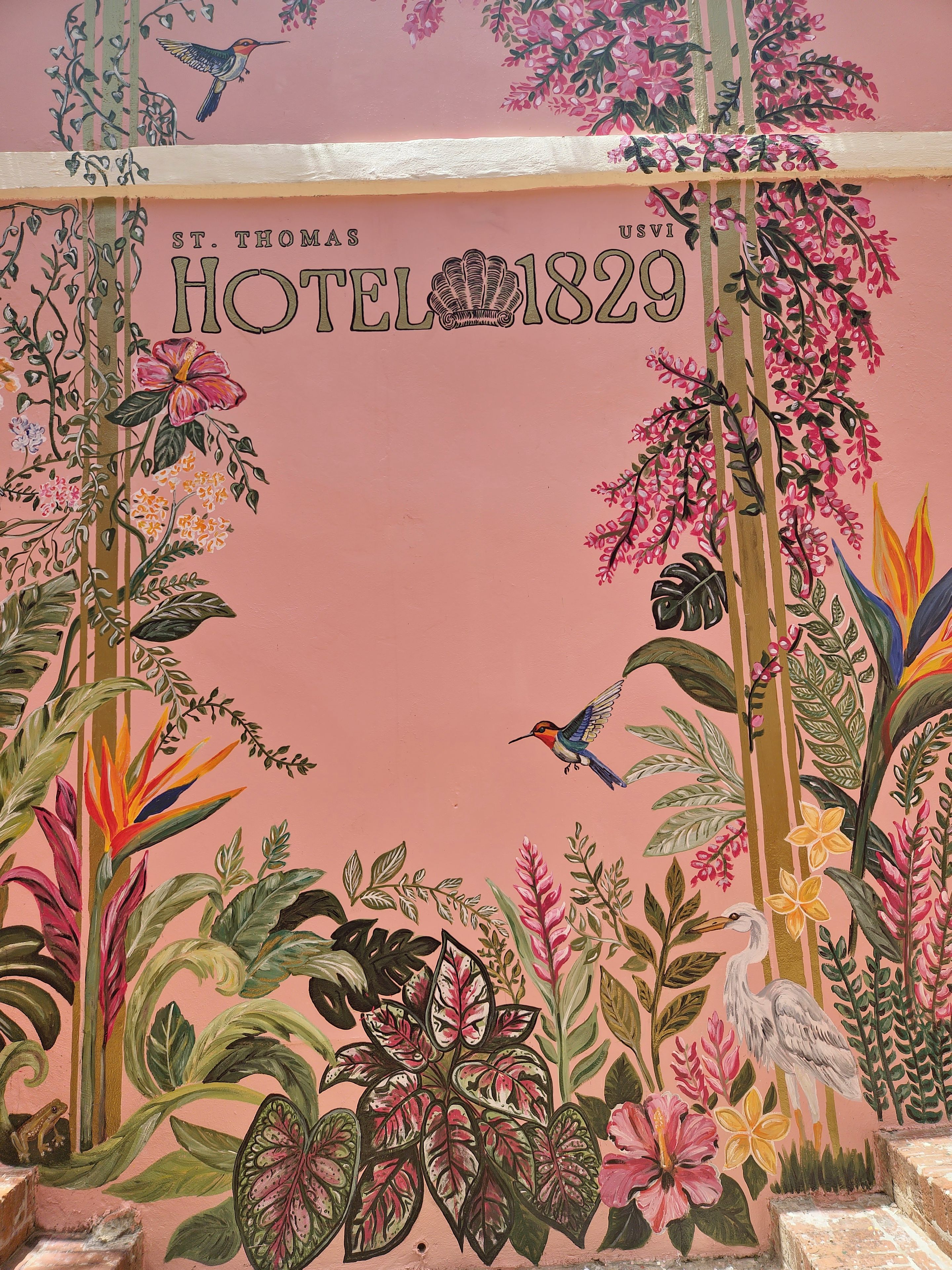 A wall with a floral and bird mural, the text 'HOTEL 1829' and 'ST. THOMAS' indicating the hotel's name and location.