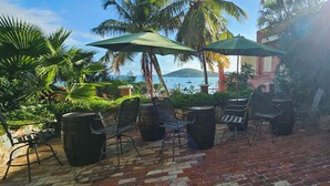 An outdoor seating area with brick flooring, metal chairs, and green umbrellas. - Hotel 1829 (St. Thomas)