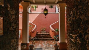 A stone archway leading to a staircase with potted plants and a hanging lantern. - Hotel 1829 (St. Thomas)