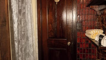 Een badkamer met een houten deur, betegelde wanden, een douchegordijn en een handdoekhouder.