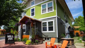 Welcome to the charming Mill Inn Bed & Breakfast, featuring a cozy porch with a hanging flower basket and comfortable Adirondack chairs.