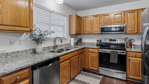 A modern kitchen with wooden cabinets, stainless steel appliances, granite countertops, and a built-in dishwasher.