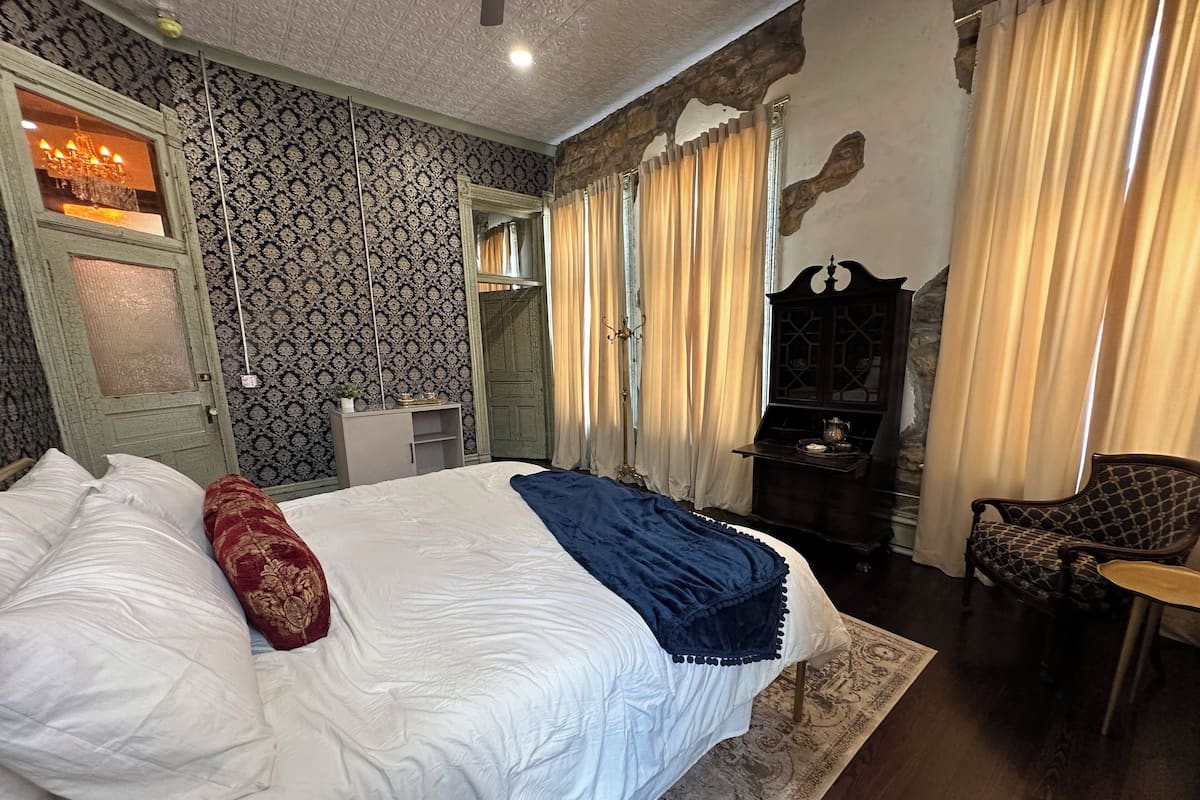 A bedroom with a large bed, a dresser, a chair, and a mirror.