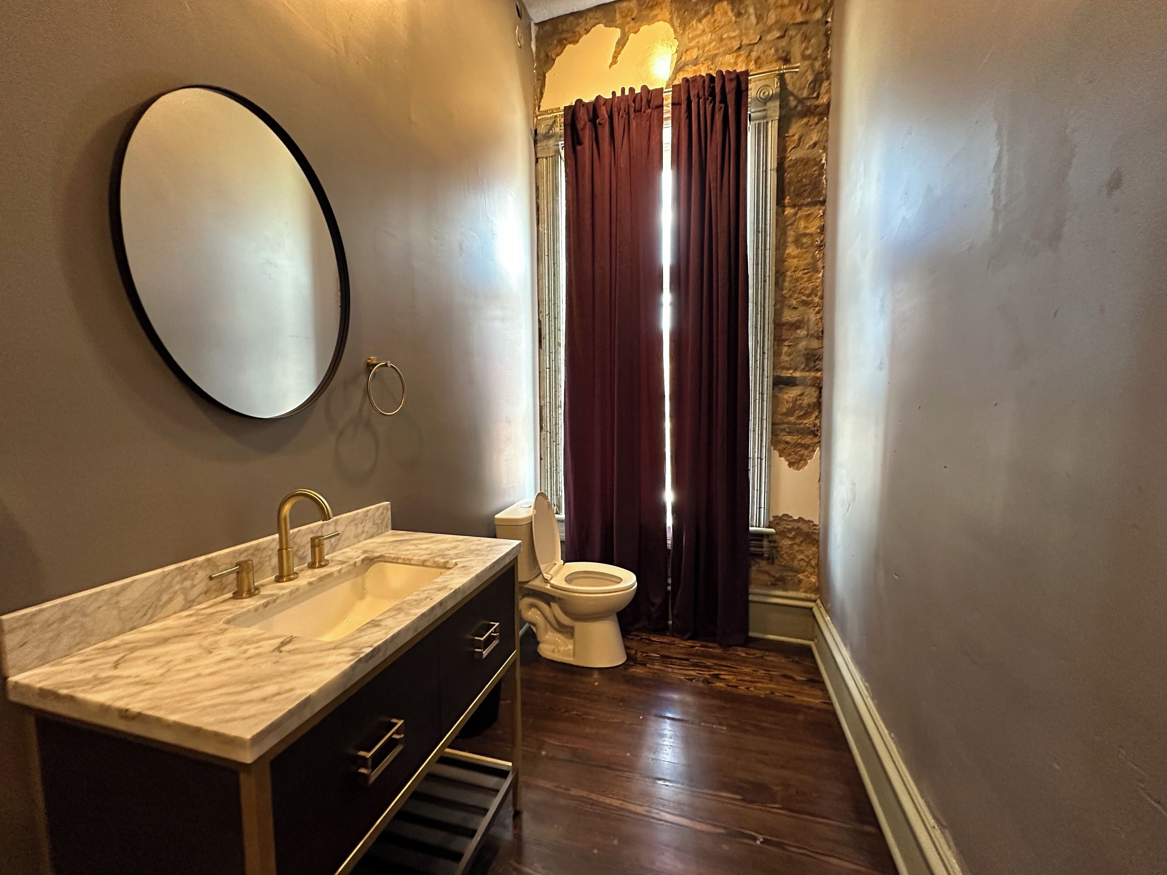 Une salle de bain avec un lavabo en marbre, des toilettes et un rideau de douche.