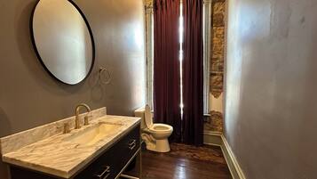 Une salle de bain avec un lavabo en marbre, des toilettes et un rideau de douche.