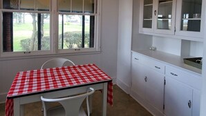 Una cocina con mantel a cuadros, armarios blancos y una lámpara colgante.