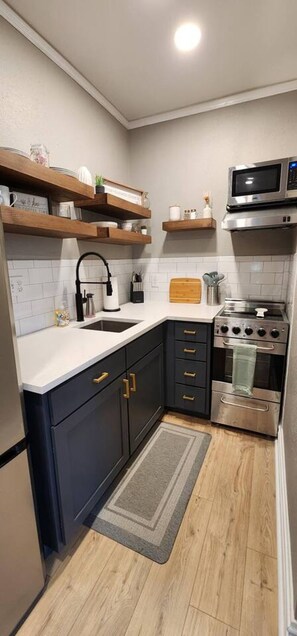 A compact kitchen with a sink, stove, and microwave. - Mahase Guest House at The Refuge (Osceola)