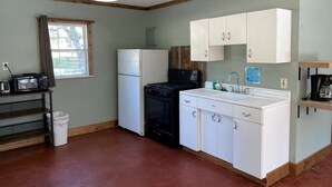 A compact kitchen with a refrigerator, stove, microwave, sink, and cabinets.