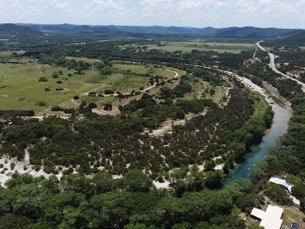 An aerial view of a river winding through a forested valley with a road curving along the river.