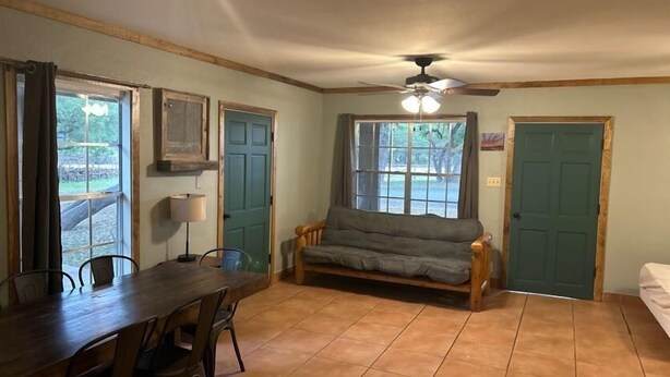 A room with a wooden dining table, chairs, a sofa, and a ceiling fan. - Riverbend on the Frio Motel 11 (Concan)