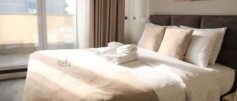 A hotel room with a bed, a window with curtains, and a cityscape view.
