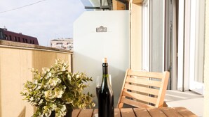 Un balcon avec une plante en pot, une bouteille de vin et une chaise en bois.