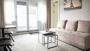 Un salon moderne avec un canapé, une table basse et un tableau représentant la Tour Eiffel.