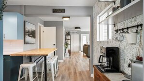 Uma cozinha moderna com uma mesa de madeira, banquetas e uma máquina de café.