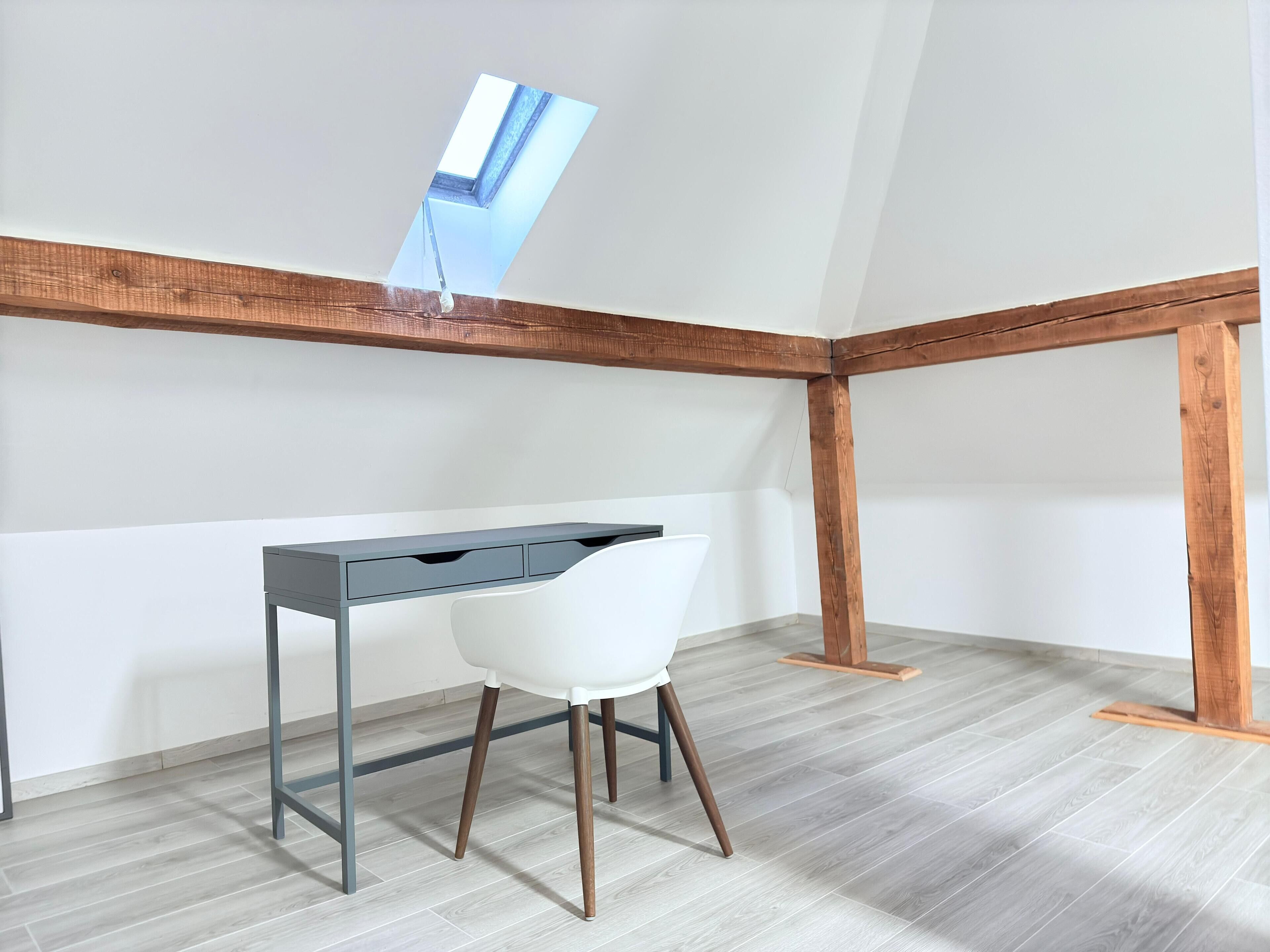 A modern office space with a desk, white chair, and wooden beams on the ceiling.
