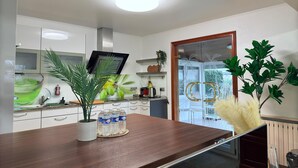 A modern kitchen with white cabinets, a wooden countertop, and a glass door leading to a balcony. - Spacious 4 bedrooms House (Strassen)