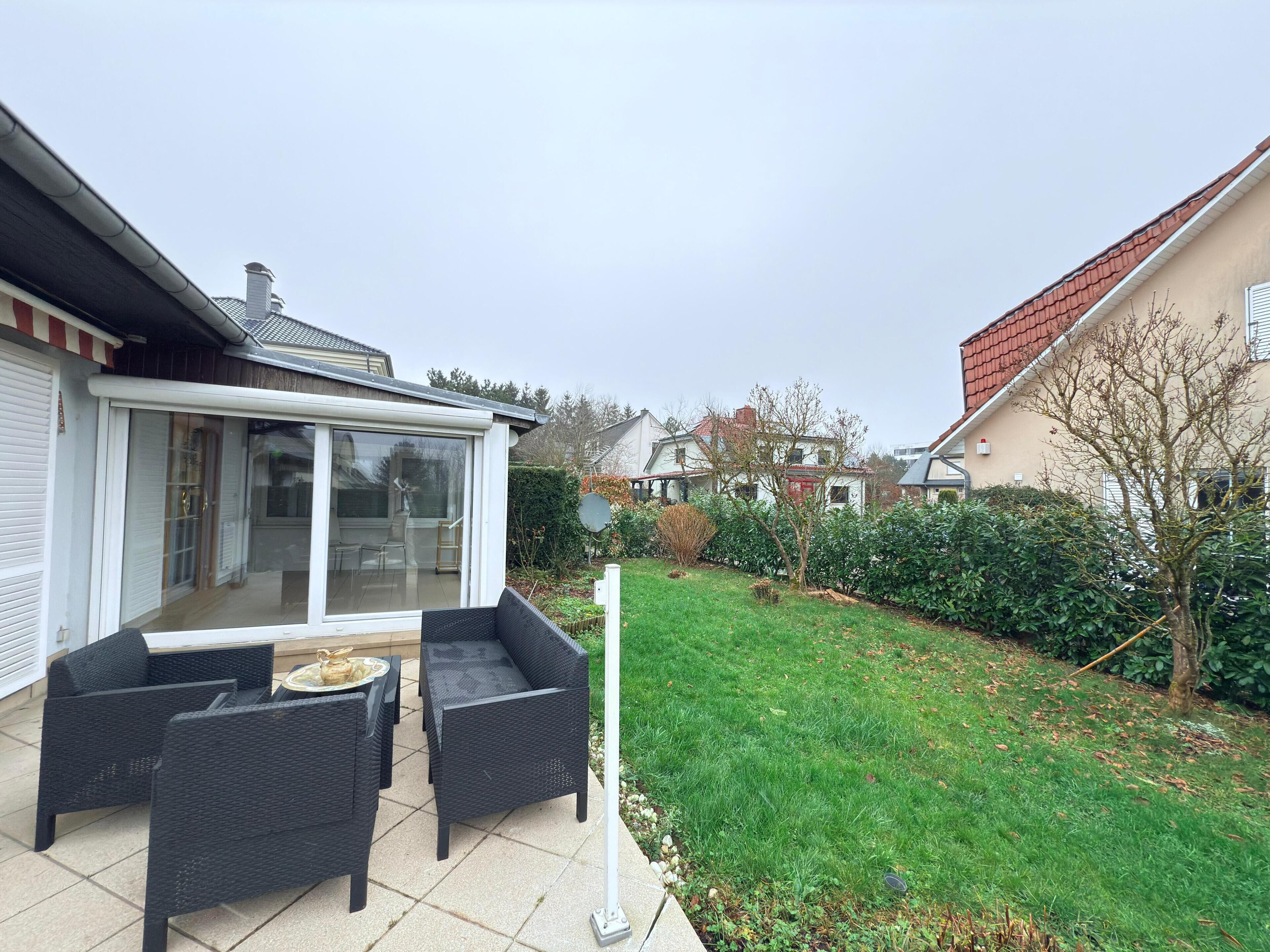 Een terras met rieten meubilair en een glazen deur naar een kamer.