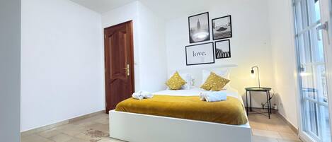 A modern bedroom with a large bed, a wooden door, and a window.