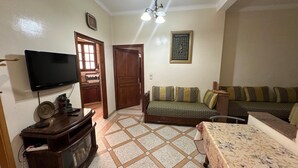 Ein Wohnzimmer mit Flachbildfernseher, Holzschrank, Sofa und Esstisch.