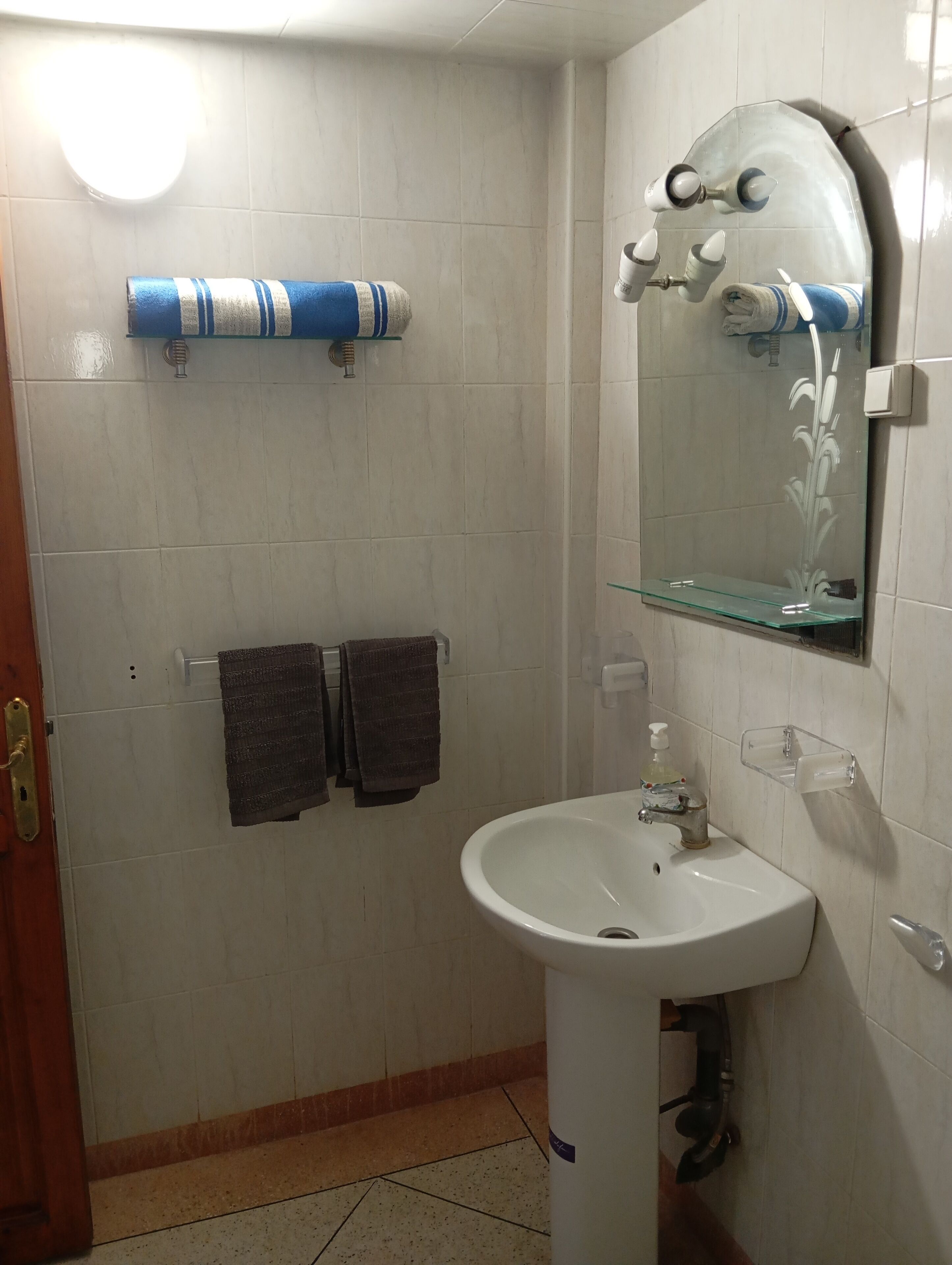 Ein Badezimmer mit einem weißen Waschbecken, einem Spiegel und einem Handtuchhalter mit zwei Handtüchern.