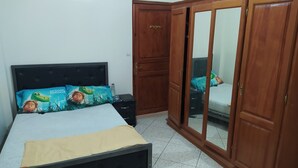 Ein Schlafzimmer mit Bett, Nachttisch, Kleiderschrank und Spiegel.