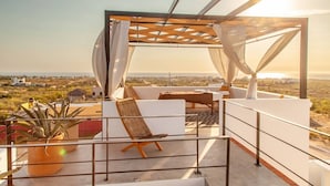 Eine Dachterrasse mit einer Pergola, einer Sitzgelegenheit und Blick auf die Landschaft.
