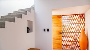 Ein modernes Interieur mit einer Treppe, einer Holztür mit Gitterwerk und einer großen Vase.