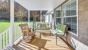 Eine überdachte Veranda mit Schaukelstuhl, Bank und Sofa.
