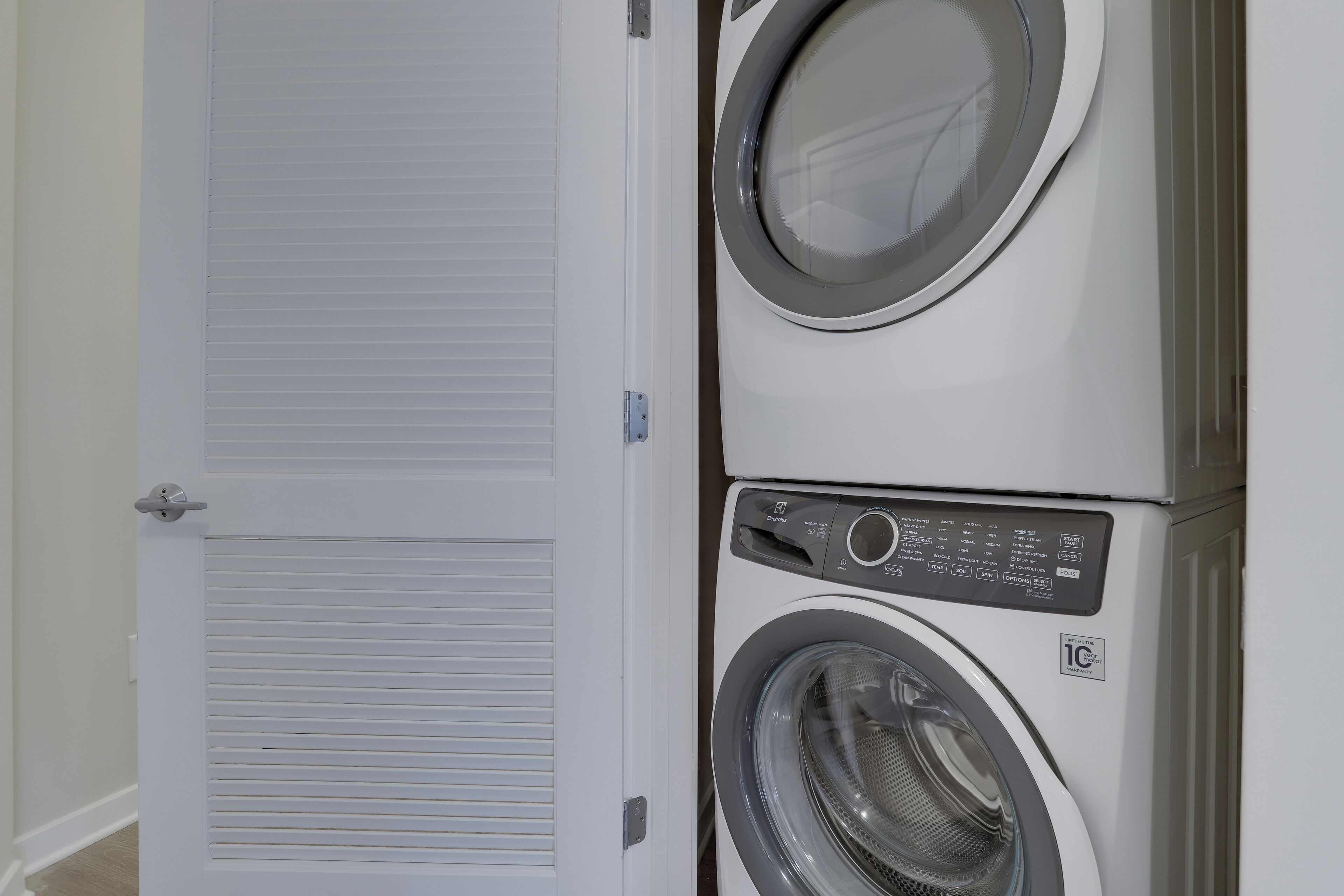 A stacked washer and dryer unit with a control panel and a door with a louvered window.