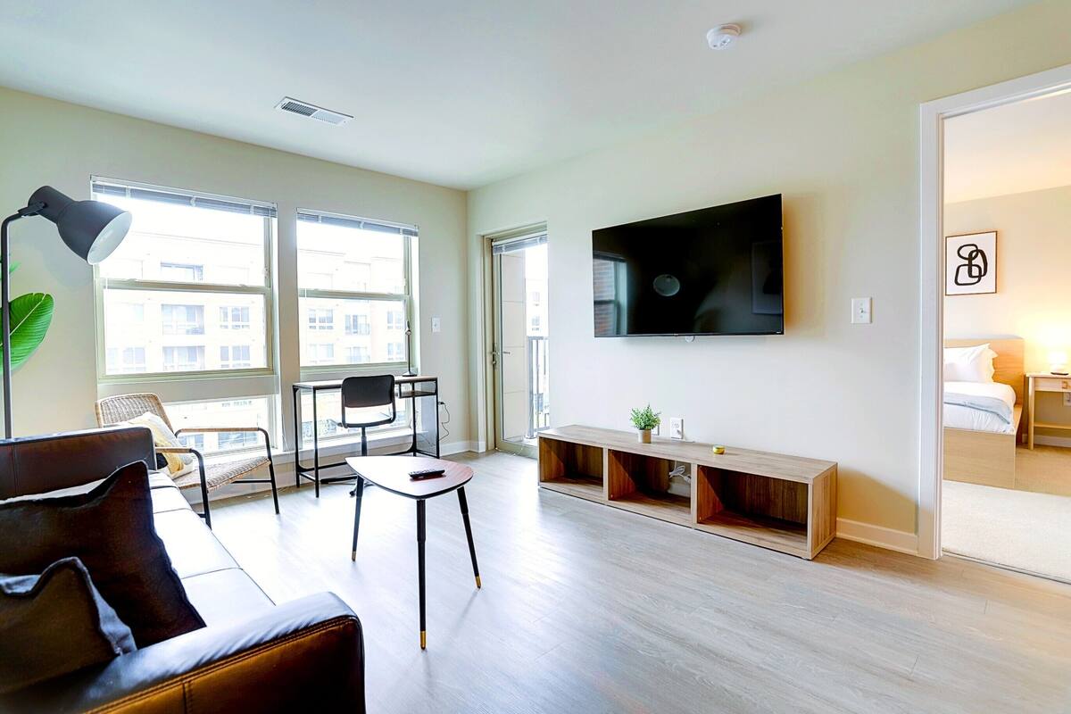 A modern living room with a sofa, a chair, a TV, and a wooden bench.