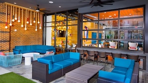 A modern outdoor seating area with blue sofas and chairs, a small table, and hanging lights. - Charming DC Area Apartments (Alexandria)
