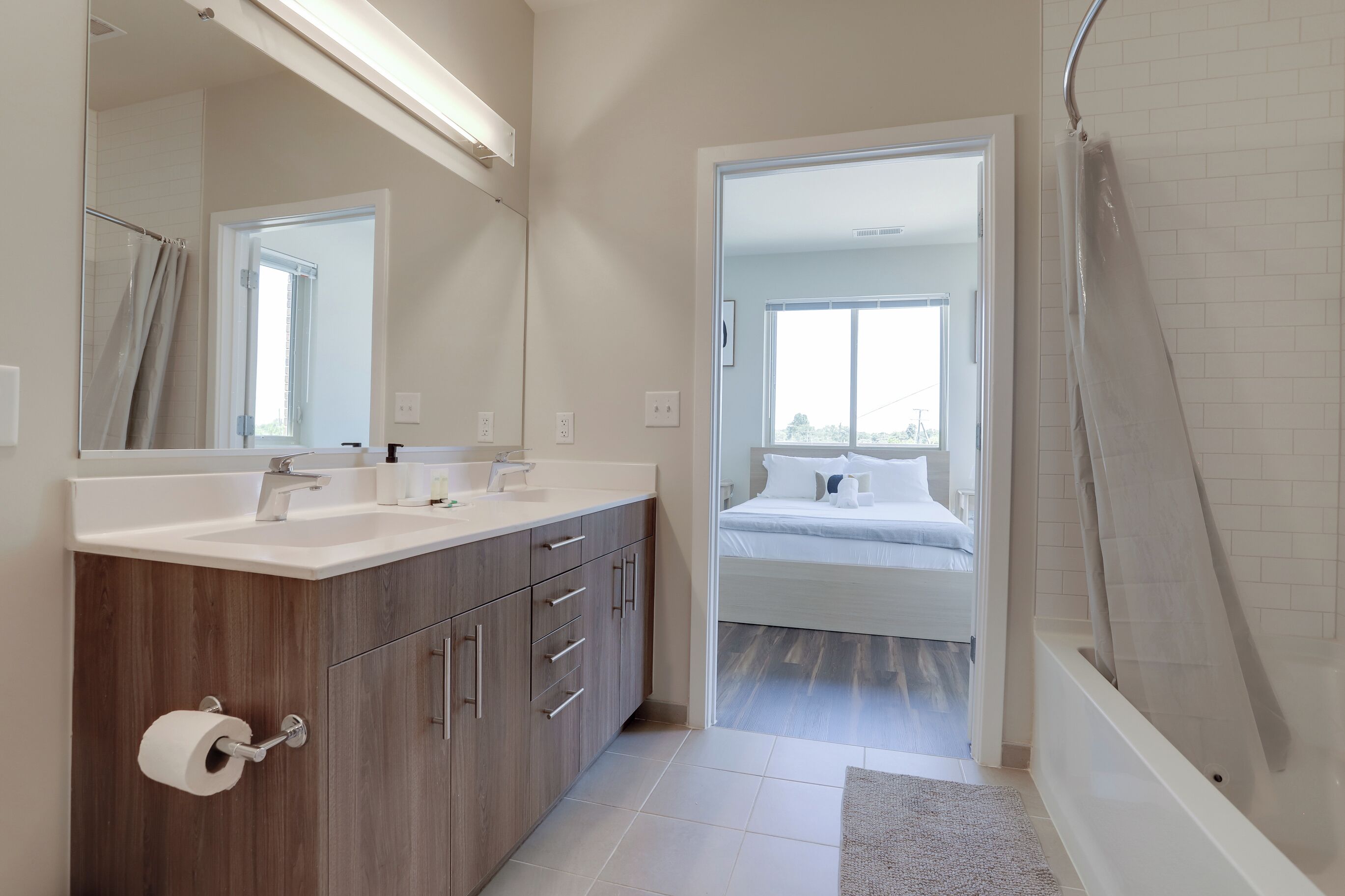 A modern bathroom with a shower, a toilet paper holder, and a mirror.