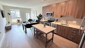 Una cocina moderna con armarios de madera, electrodomésticos de acero inoxidable y un comedor con mesa y sillas.