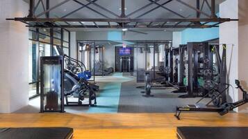 A gym with cardio machines, weightlifting equipment, and a mirrored wall.