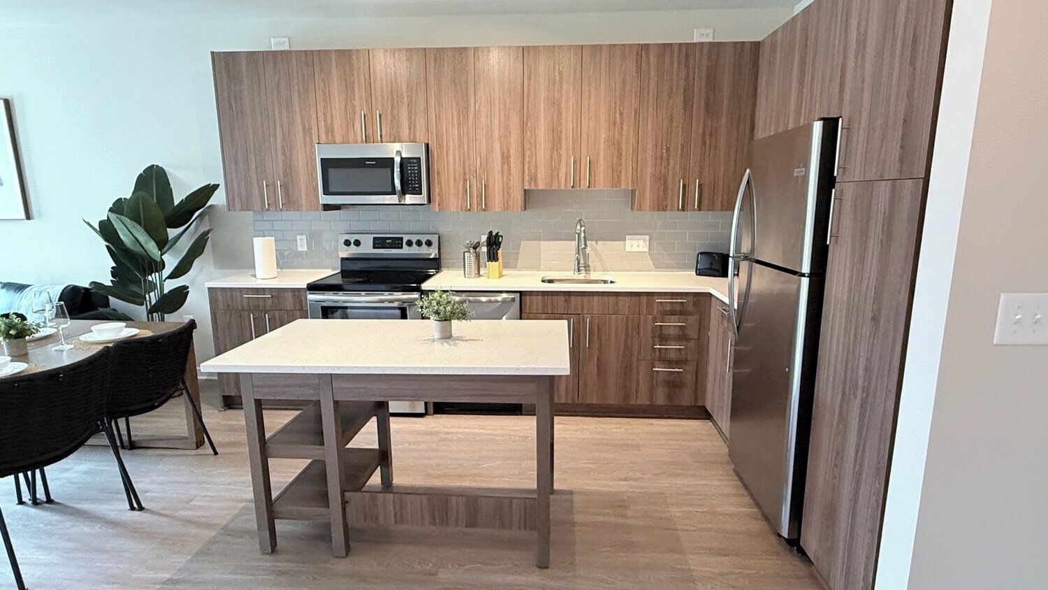 Una cocina moderna con armarios de madera, un refrigerador de acero inoxidable, un microondas y una estufa.