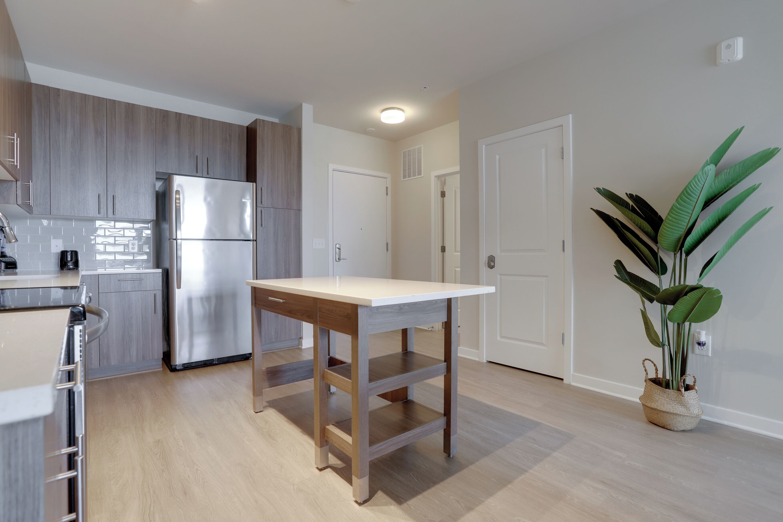 Een moderne keuken met een roestvrijstalen koelkast, houten kastjes en een lichtgekleurd aanrecht.