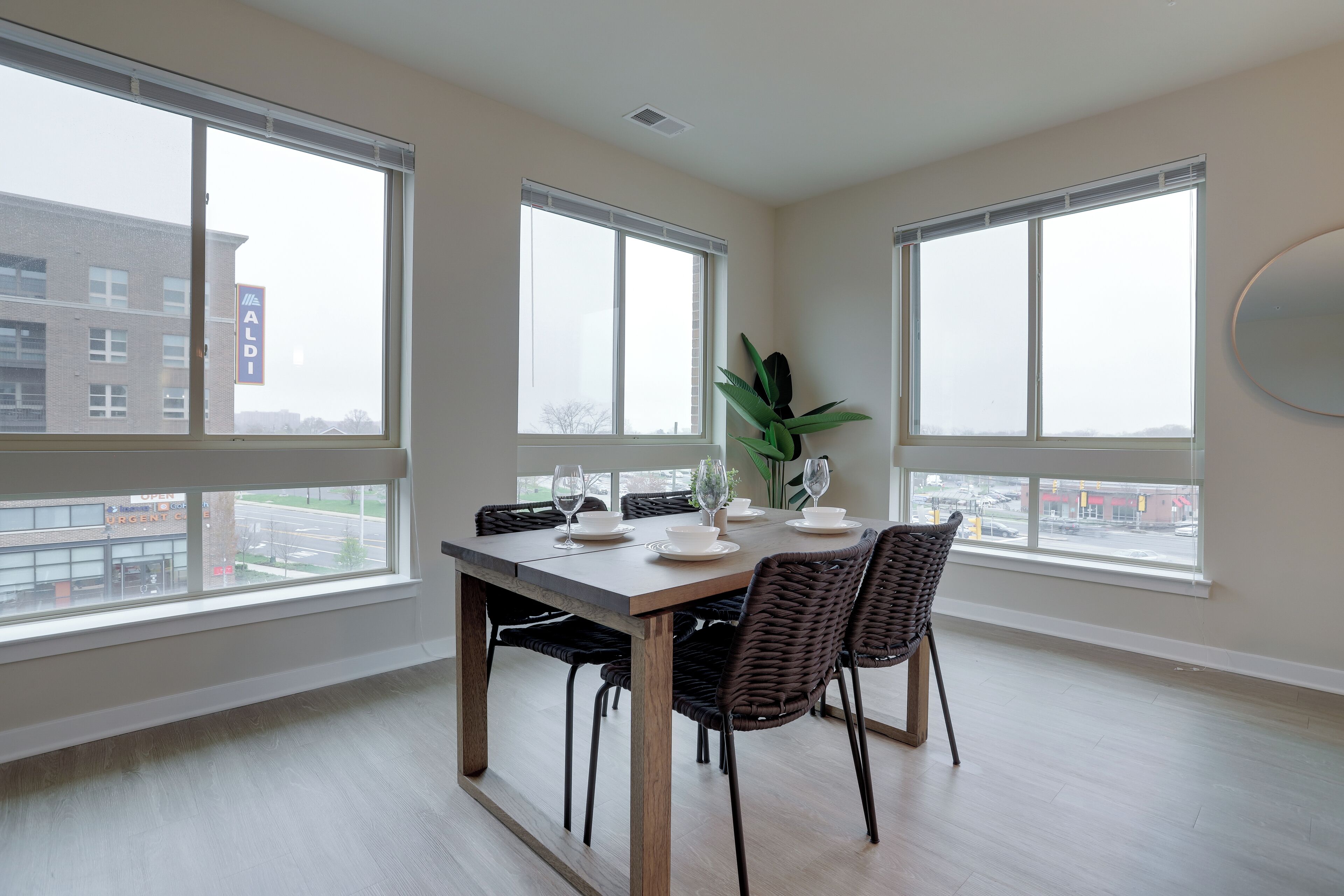 A dining area with a large table, chairs, and a view of the outside through large windows.