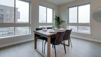 A dining area with a large table, chairs, and a view of the outside through large windows.