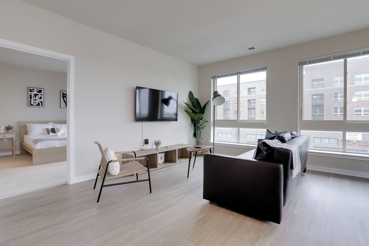 A modern living room with a bed, a sofa, a TV, and a desk.