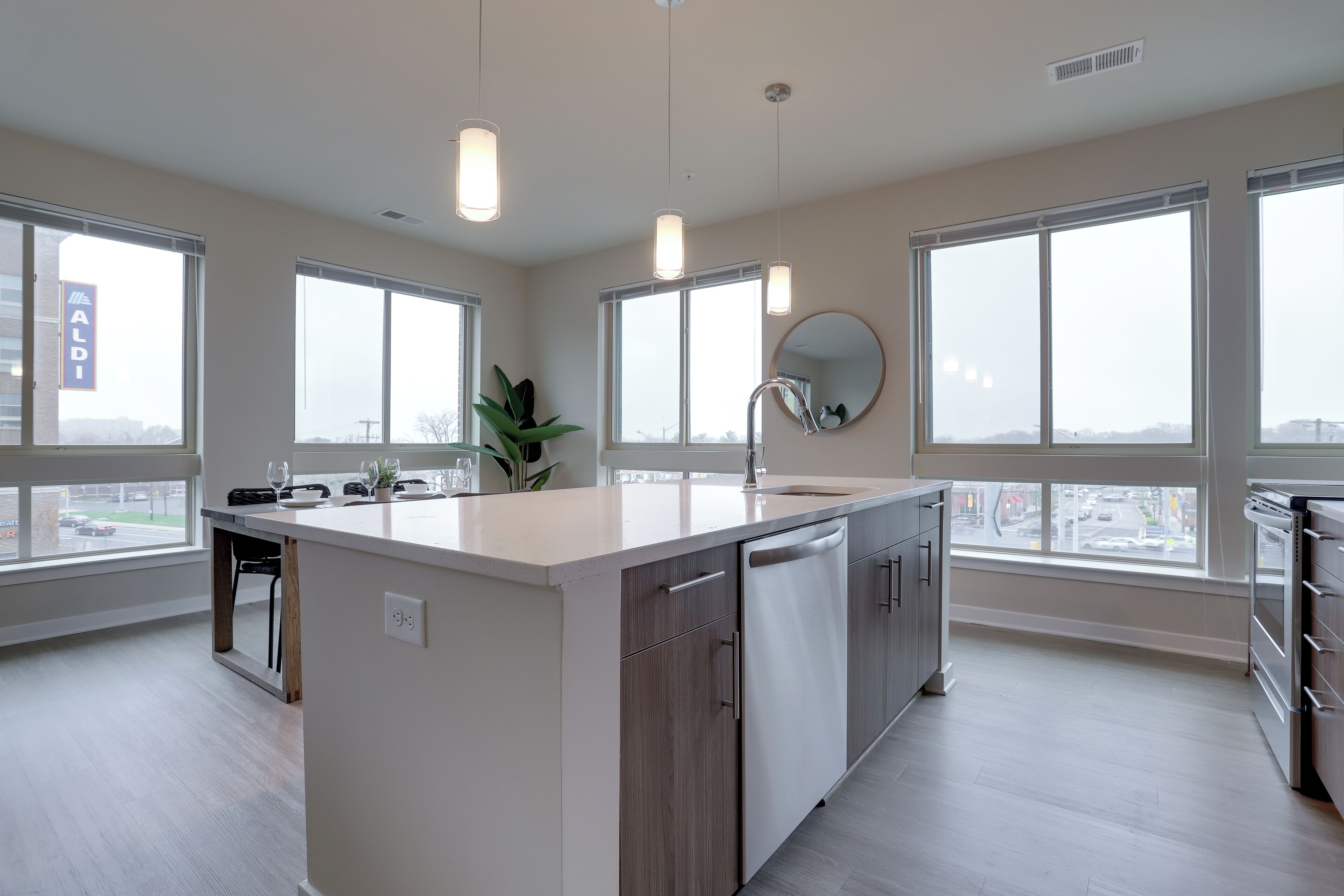 A modern kitchen with a central island, large windows, and a view of the city.