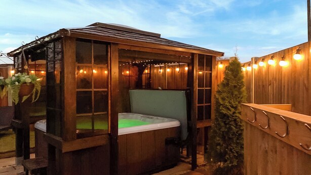 Un jacuzzi en un quiosco de madera con luces colgantes.
